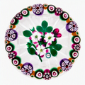 Made in 2025 by Peter Holmes, this Floral Bouquet with Cane Garland is one of my favorites. 3 white and pink flowers with buds, stems and leaves completing a bouquet surrounded by an alternating pattern of 4 distinct designs of complex canes. Clear ground, star cut base, PH signature cane viewed from above. 3.5”