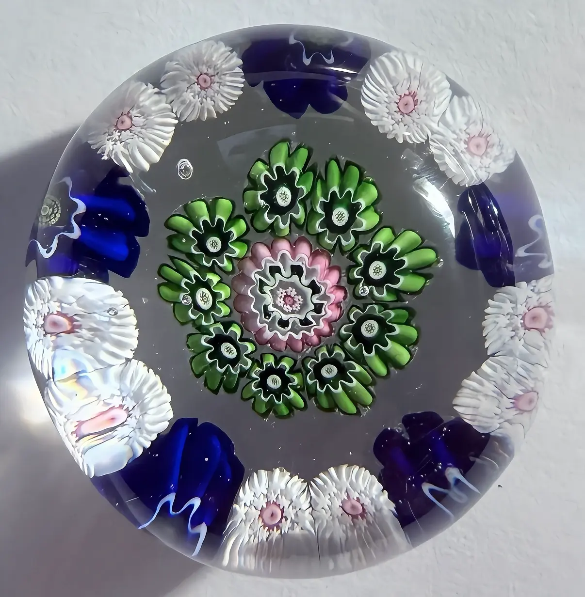Antique Clichy with outer ring pattern of two white stardust canes with pink centers and one blue pastry mold complex canes with green centers,an inner ring of 9 green pastry molds surrounding a nice pink pastry mold center complex cane. Clear Ground. High flat dome. 1.62"