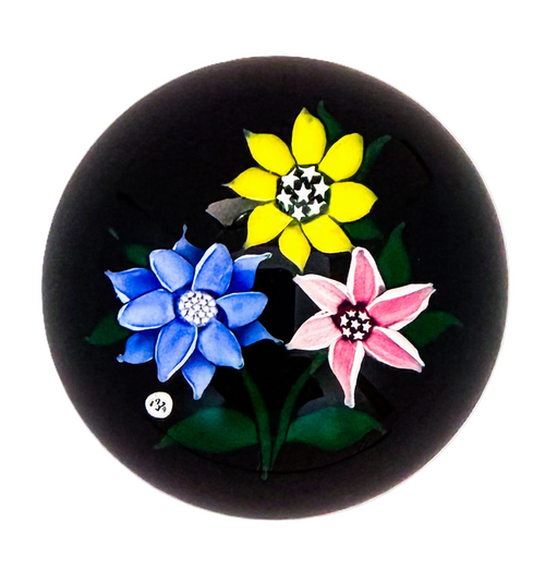 1979 J Glass Blue, yellow and pink flowerheads with stardust center canes atop an opaque black ground, J 1979 cane floats next to the blue flowerhead. Delicate lampwork at it;s finest with wonderfully cupped petals on each flower.&nbsp; A near perfect weight at a great price, easily one of the best among it's contemporaries in 1979.&nbsp; 2 1/4"